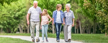 Couple de grands parents accompagnés de leurs petits-enfants se promenant dans un parc